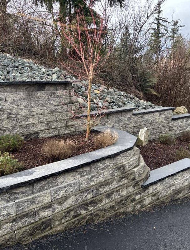 Tiered stone retaining wall with dark capstones in Oak Harbor