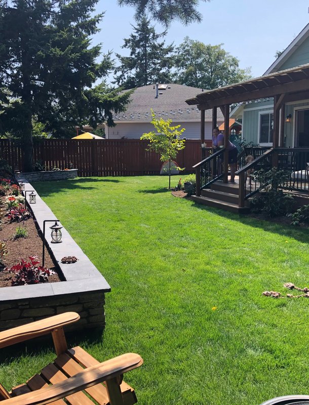 Finished Oak Harbor backyard with lawn, garden wall, and deck
