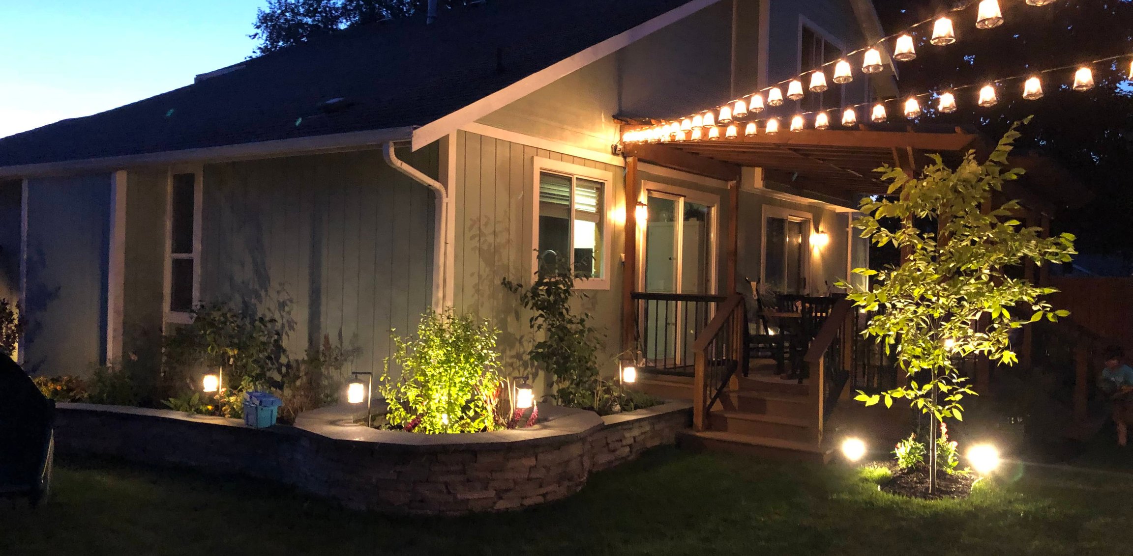 Backyard patio, pergola, and landscape lighting at dusk in Oak Harbor