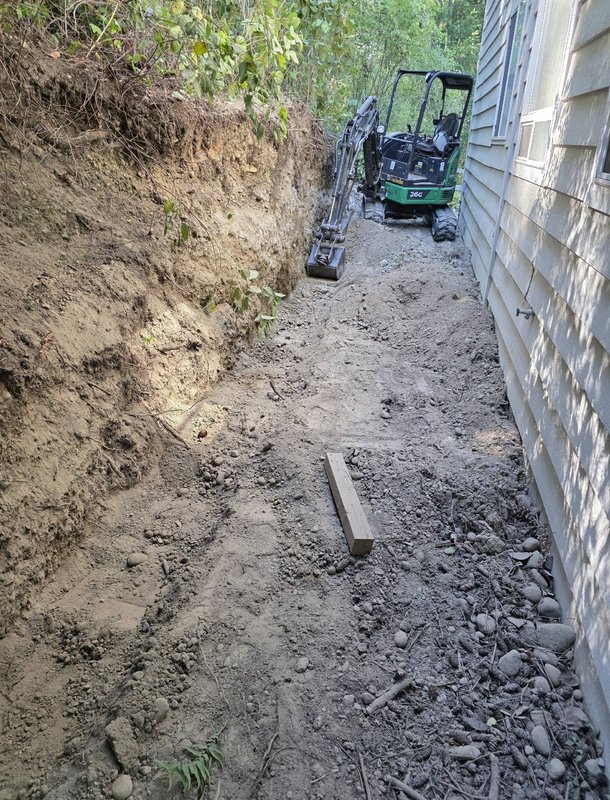 Mini excavator trenching for a retaining wall on Whidbey Island